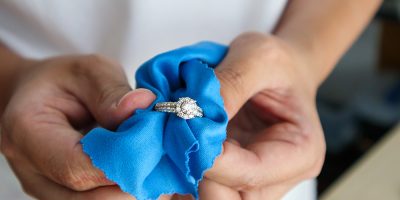 Jeweller hand polishing and cleaning jewelry diamond ring with m Jeweller hand polishing and cleaning jewelry diamond ring with micro fiber fabric